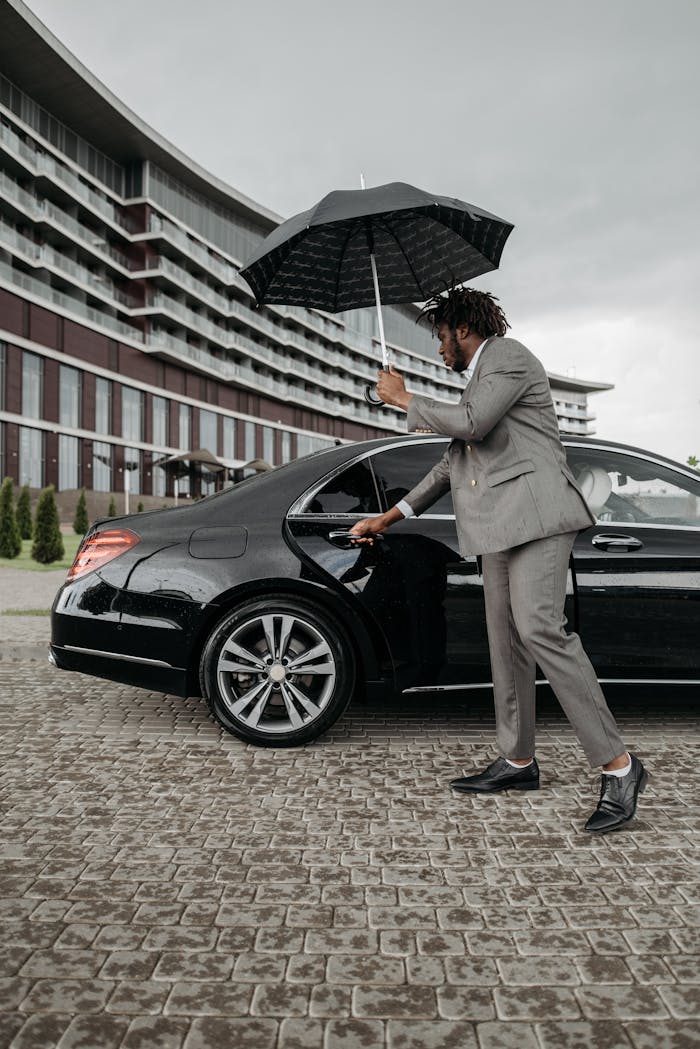 A Man in Gray Suit Opening the Door of a Black Car
